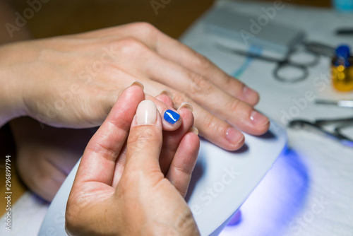 Beautiful manicure process. Nail polish being applied to hand, polish is a blue color. close up © jollier_