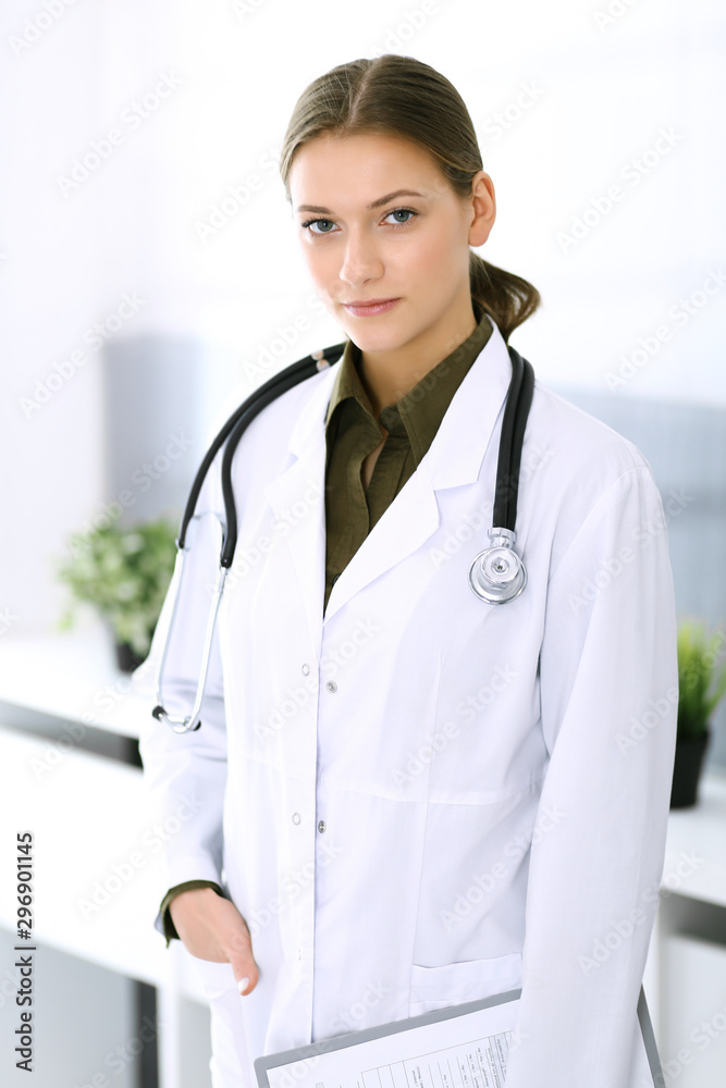 Doctor woman standing straight and looking at camera. Perfect medical service in clinic. Happy future in medicine and healthcare Doctor woman standing straight and looking at camera. Perfect medical service in clinic. Happy future in medicine and healthcare