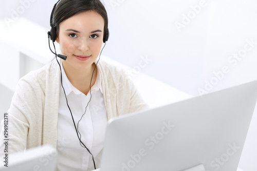 Call center. Beautiful woman receptionist sitting in headset at customer service office. Group of operators at work. Business concept photo