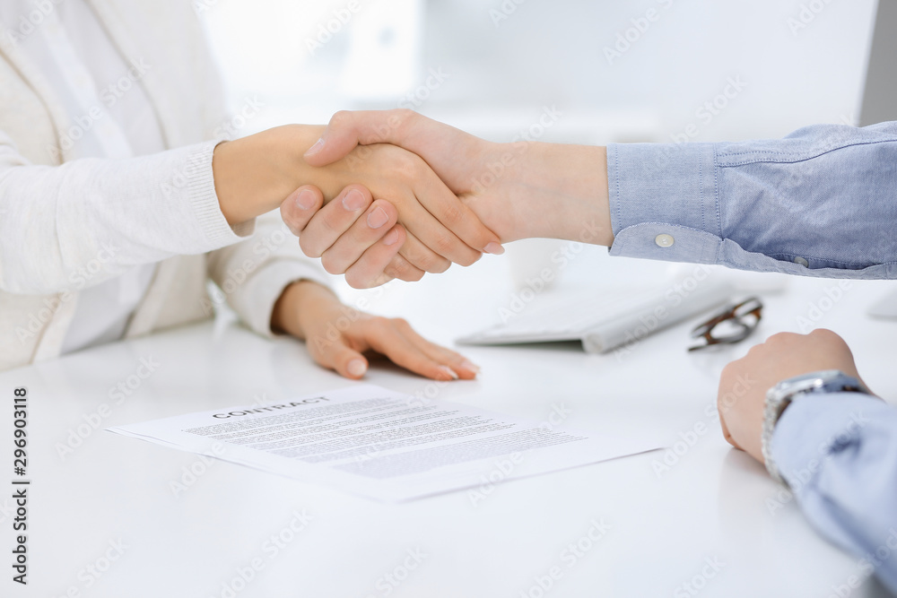 Business people shaking hands at meeting or negotiation after contract discussing. Businessman and woman handshake at office while sitting at the desk. Success concept Business people shaking hands at meeting or negotiation after contract discussing. Businessman and woman handshake at office while sitting at the desk. Success concept