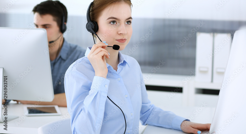 Group of operators at work. Call center. Focus on beautiful woman receptionist in headset at customer service. Business concept and casual clothing style Group of operators at work. Call center. Focus on beautiful woman receptionist in headset at customer service. Business concept and casual clothing style
