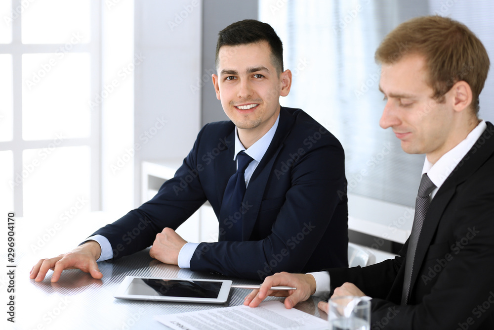 Businessmen or partners working together while using tablet computer at the desk in modern office. Headshot of male entrepreneur or manager with colleague at workplace. Teamwork, partnership and Businessmen or partners working together while using tablet computer at the desk in modern office. Headshot of male entrepreneur or manager with colleague at workplace. Teamwork, partnership and