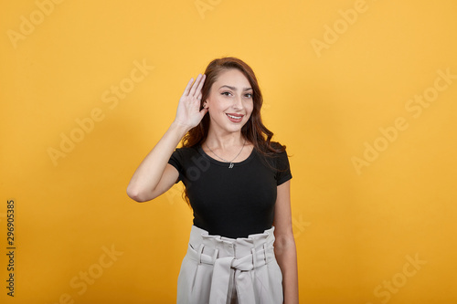 Girl trying to listen something as points on her ear. She is using her hand to clear the sound to listen properly.