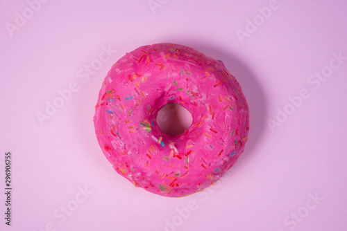 Sweet donut decorated with colorful icing isolated on pink background. Bright tasty bun. Minimal summer concept. Copy space. Flat lay. The concept of not healthy eating and weight gain