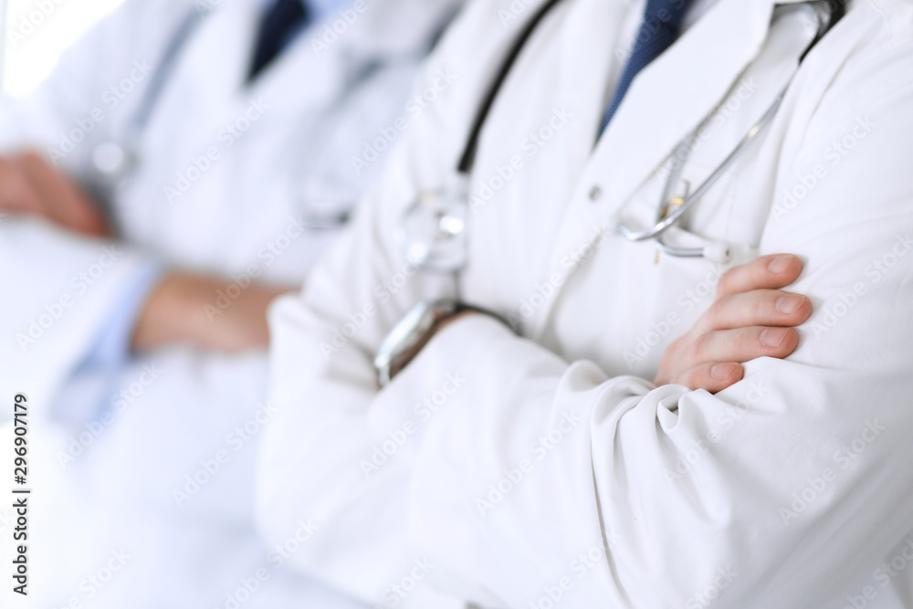 Group of modern doctors standing as a team with arms crossed in hospital office, close-up. Physicians ready to examine and help patients. Medical help, insurance in health care, best treatment and Group of modern doctors standing as a team with arms crossed in hospital office, close-up. Physicians ready to examine and help patients. Medical help, insurance in health care, best treatment and