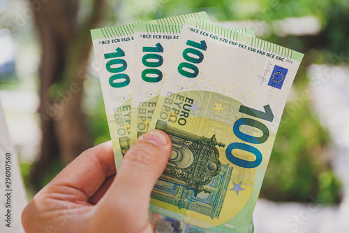 Tableau sur toile Male hand holding 100 hundredth euro banknotes on green background