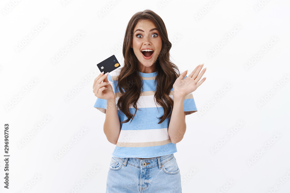 Fototapeta premium Girl sharing wonderful banking promo, smiling amused popping eyes camera enthusiastic and wondered, gesturing raised hand, hold credit card, impressed how much cashback, paying for shopping