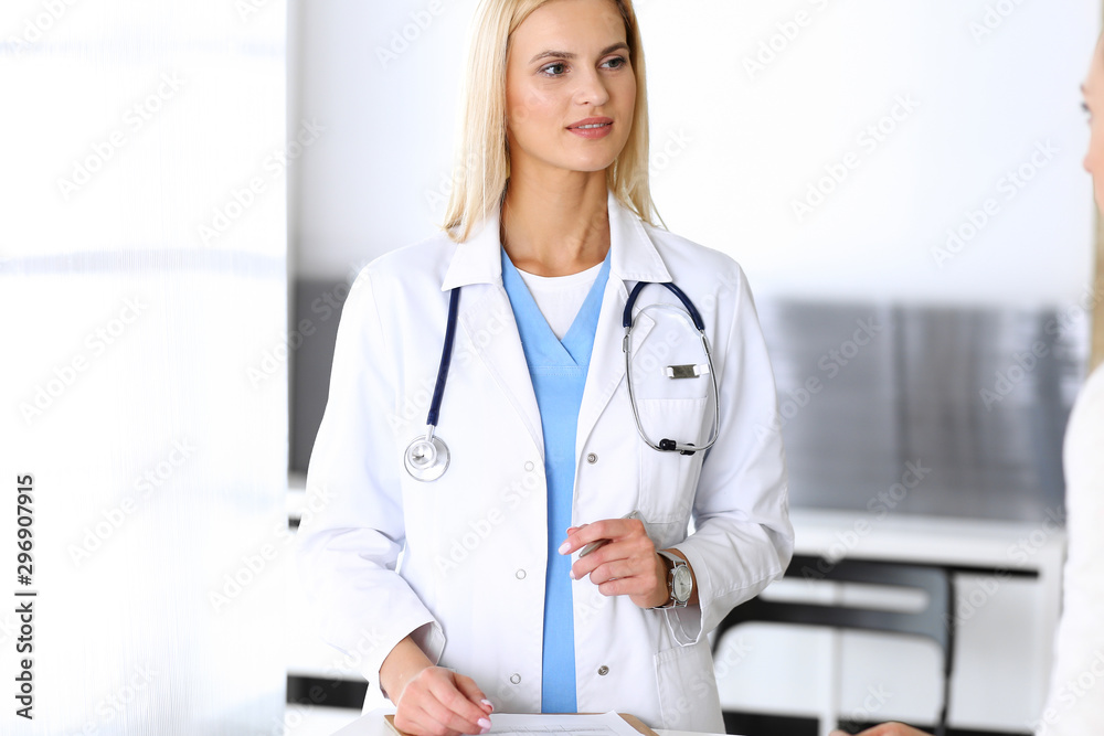 Doctor woman at work in hospital excited and happy of consulting female patient. Blonde physician controls medication history records and exam results while using clipboard. Medicine and healthcare Doctor woman at work in hospital excited and happy of consulting female patient. Blonde physician controls medication history records and exam results while using clipboard. Medicine and healthcare