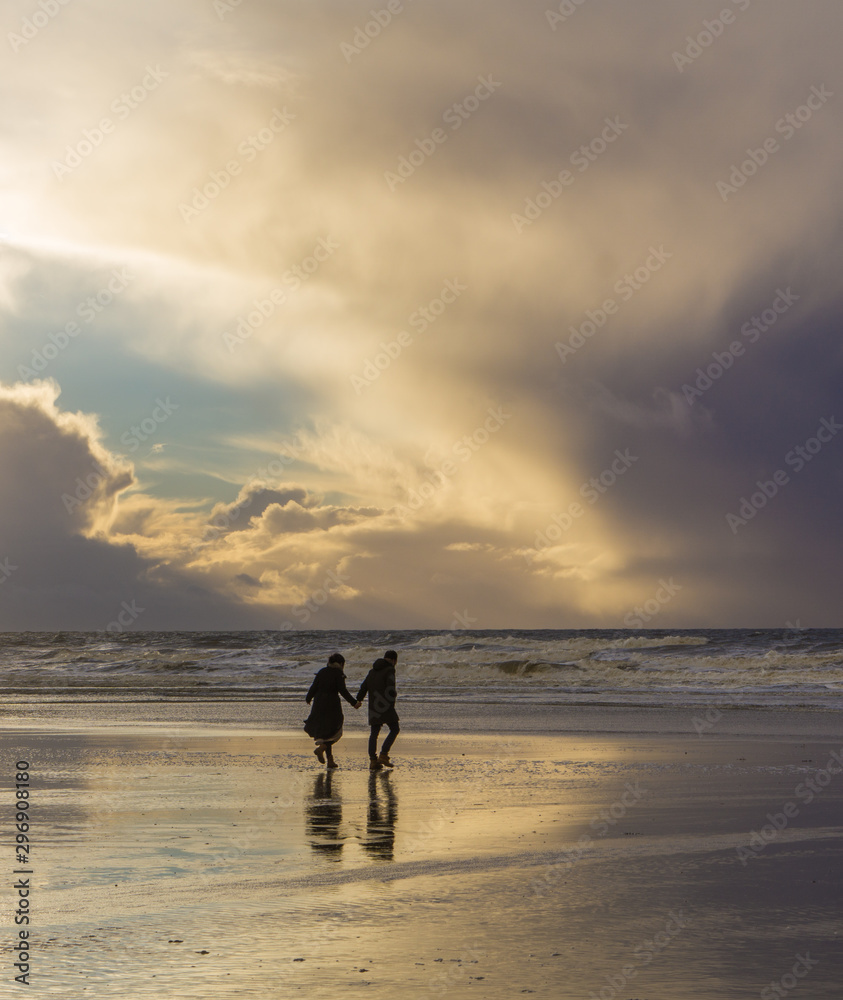 Naklejka premium silhouette of couple holding hands on the beach at sunset