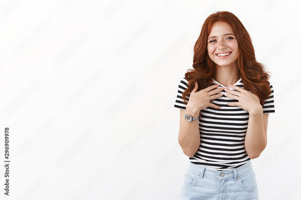 Tender lovely redhead teenage girl in striped t-shirt look pleased and happy, smiling sincere, press palms to chest touched with nice cute gift, looking thankful, grateful for help, white background Tender lovely redhead teenage girl in striped t-shirt look pleased and happy, smiling sincere, press palms to chest touched with nice cute gift, looking thankful, grateful for help, white background