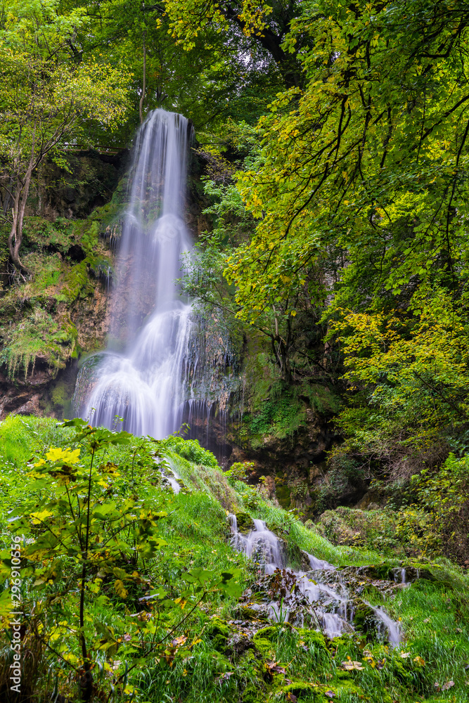 Germany, Amazing tall 37 meters high waterfall of bad urach in climatic spa region of swabian alb nature landscape hidden in green jungle like forest, a popular tourist attraction