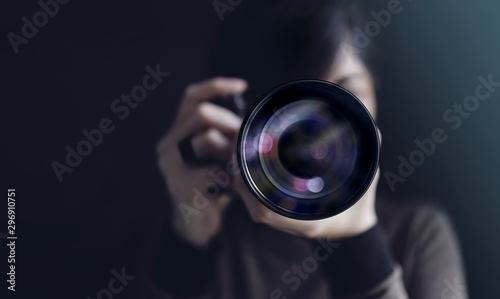 Photographer Taking Self-Portrait. Woman using Camera to Taking Photo. Dark Tone, Front View. Selective focus on Lense. Straight into a Camera photo