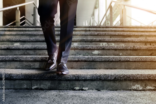 Motivation and challenging Career Concept. Steps into a Success. Low Section of Businessman Walking Down on Staircase. Male in Black Formal Dress