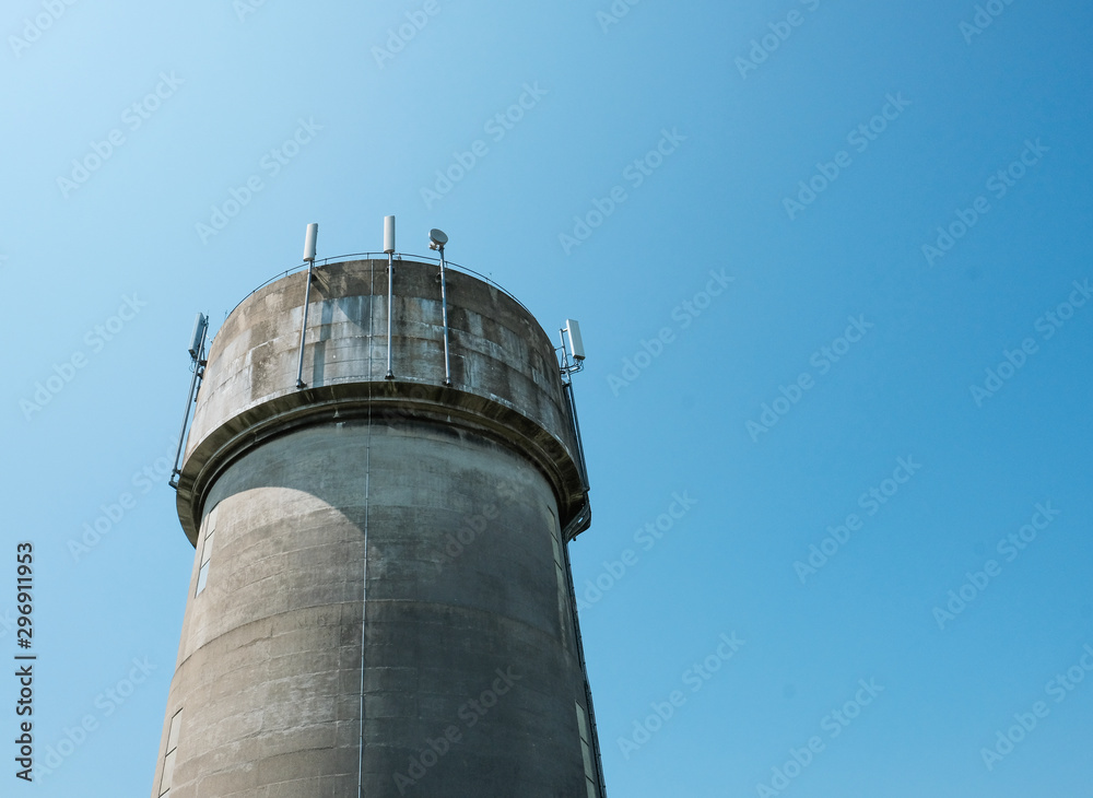 Large concrete water tower showing mobile phone communications antennas attached.