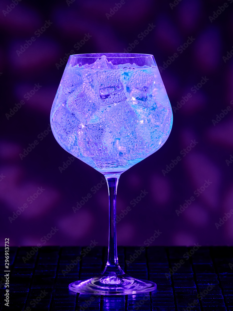 Gin tonic under blacklight (UV) illumination. Glow in the dark drink. Stock Photo Adobe Stock