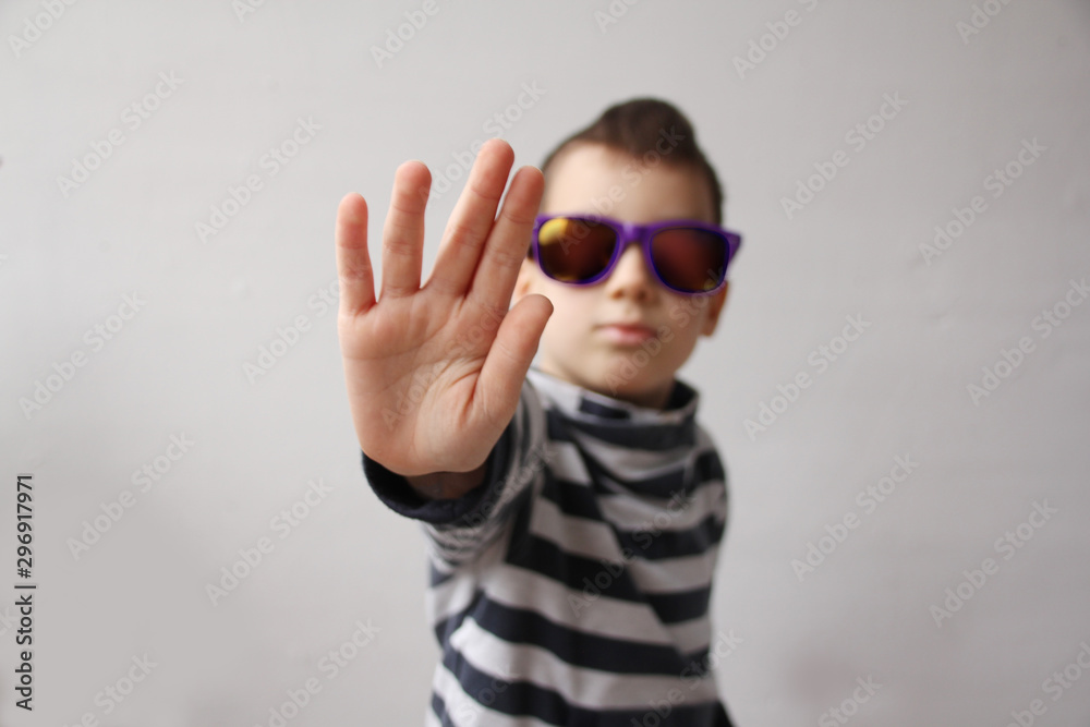 boy in dark sunglasses with a mohawk on his head closes his palm, STOP gesture, selective focus on the hand, protest concept, close-up, psychological and physical abuse concept, humiliation boy in dark sunglasses with a mohawk on his head closes his palm, STOP gesture, selective focus on the hand, protest concept, close-up, psychological and physical abuse concept, humiliation