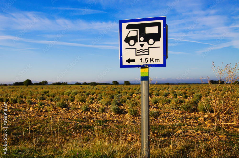 View on isolated white direction sign with camper against blue sky and lavender field. Sign gives information for next cesspool for feces disposal. Provence, France