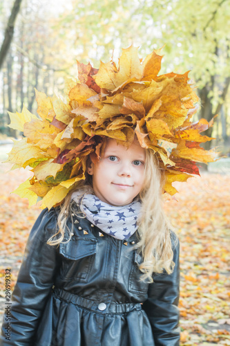 Portrait of a beautiful little girl in a wreath of maple leaves