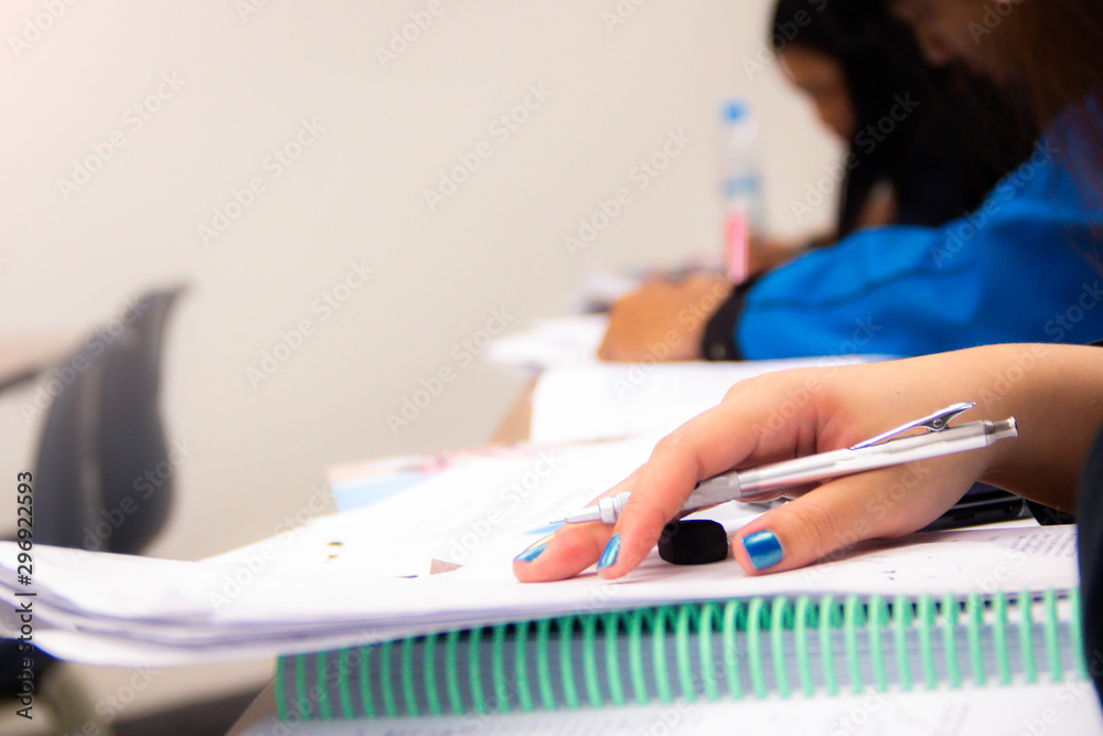 Fototapeta premium University students do quiz, test or studies from the teacher in a large lecture room. Students in uniform attending exam classroom educational school.