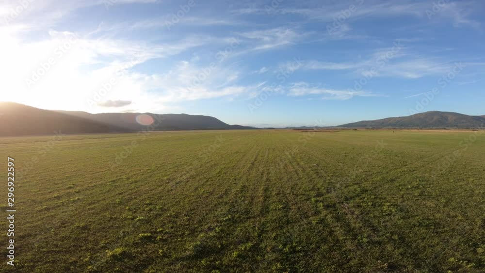 AERIAL Across a vast pasture in a valley at sunset AERIAL Across a vast pasture in a valley at sunset
