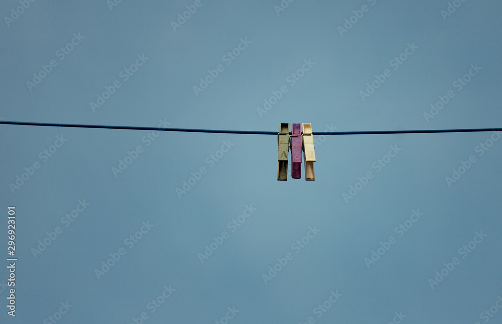 Three colored pegs on a line in front of a blue sky Three colored pegs on a line in front of a blue sky