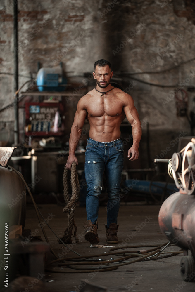 Muscled half naked man at work in an old factory.