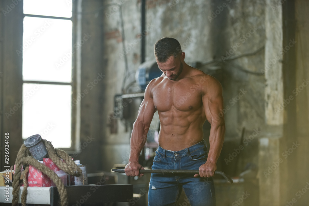 Muscled half naked man at work in an old factory.