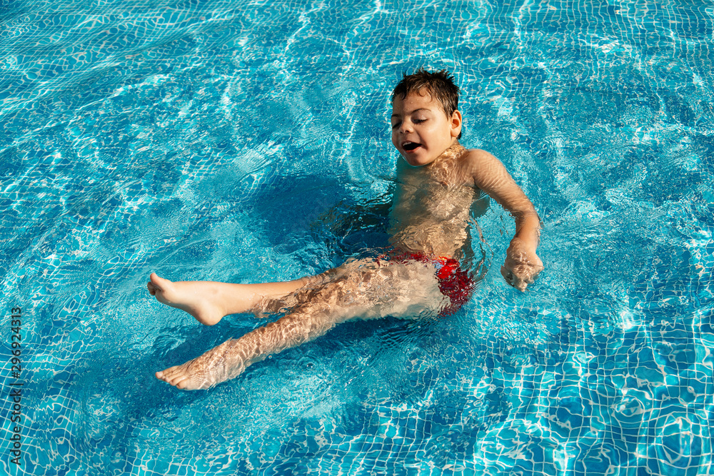 niño con discapacidad jugando y disfrutando sentado en piscina pequeña