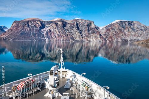Mountain landscape with reflection.  Expedition cruise ship in Sam Ford Fjord, Baffin Island in Nunavut, Arctic Canada