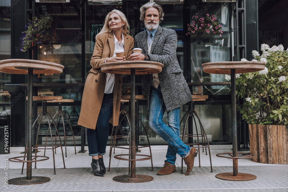 Happy adult couple enjoying coffee on the street