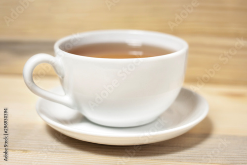 white cup of tea with plate on wooden background