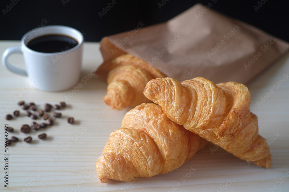 Delicious breakfast with fresh croissants and cup of espresso coffee on wood table.