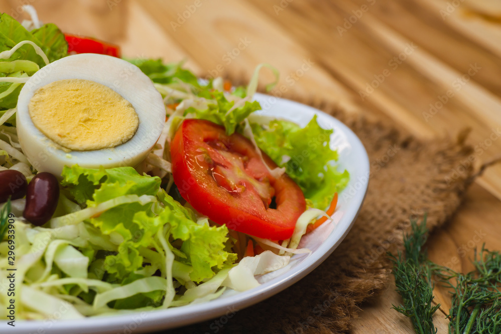 Salad bowls of vegetables and boiled eggs, healthy food on a wooden table.