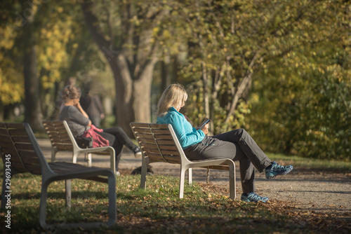 Two people sitting in the park relaxing in the autumn sun
