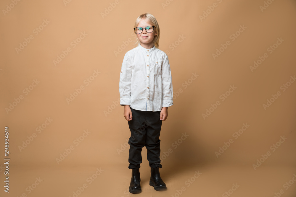 Fototapeta premium A boy in glasses dressed in white shirt, black trousers thinks about serious plans. School