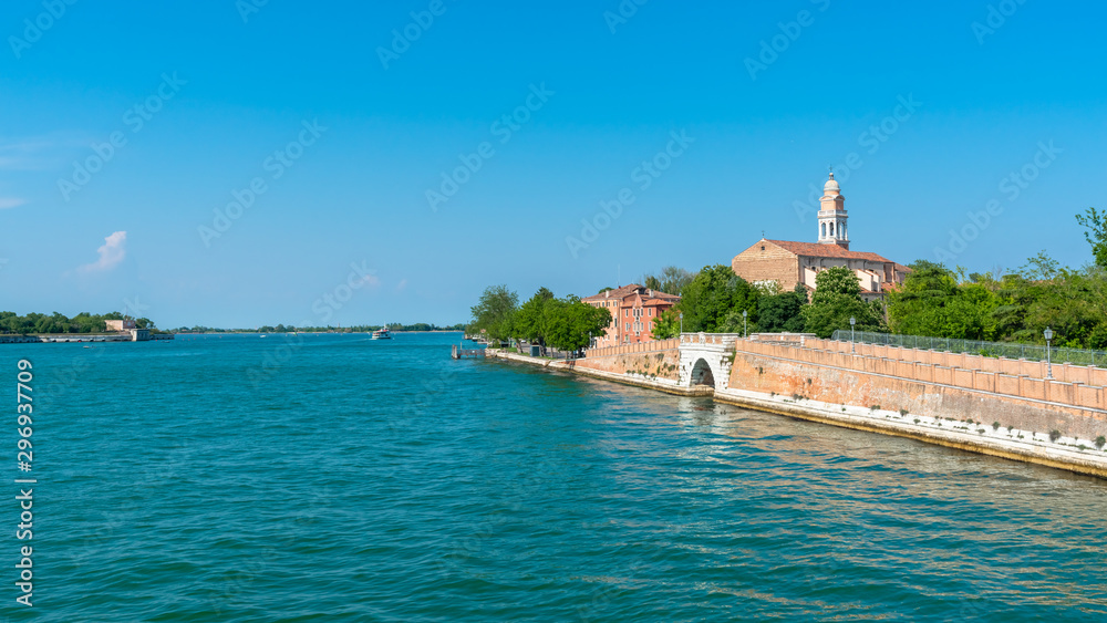 Venice. Island Lido. Panoramic view of beautiful embankment of Lido island with Saint Nicolas Church. Blue sky and green trees background. 