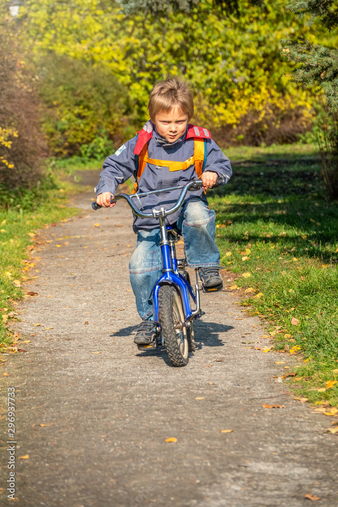 Little boy rides a bicycle in the autumn park.