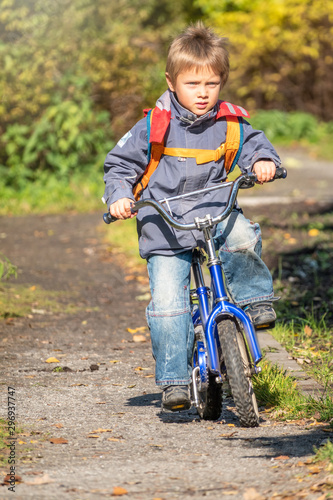 Fototapeta Naklejka Na Ścianę i Meble -  Little boy rides a bicycle in the autumn park.