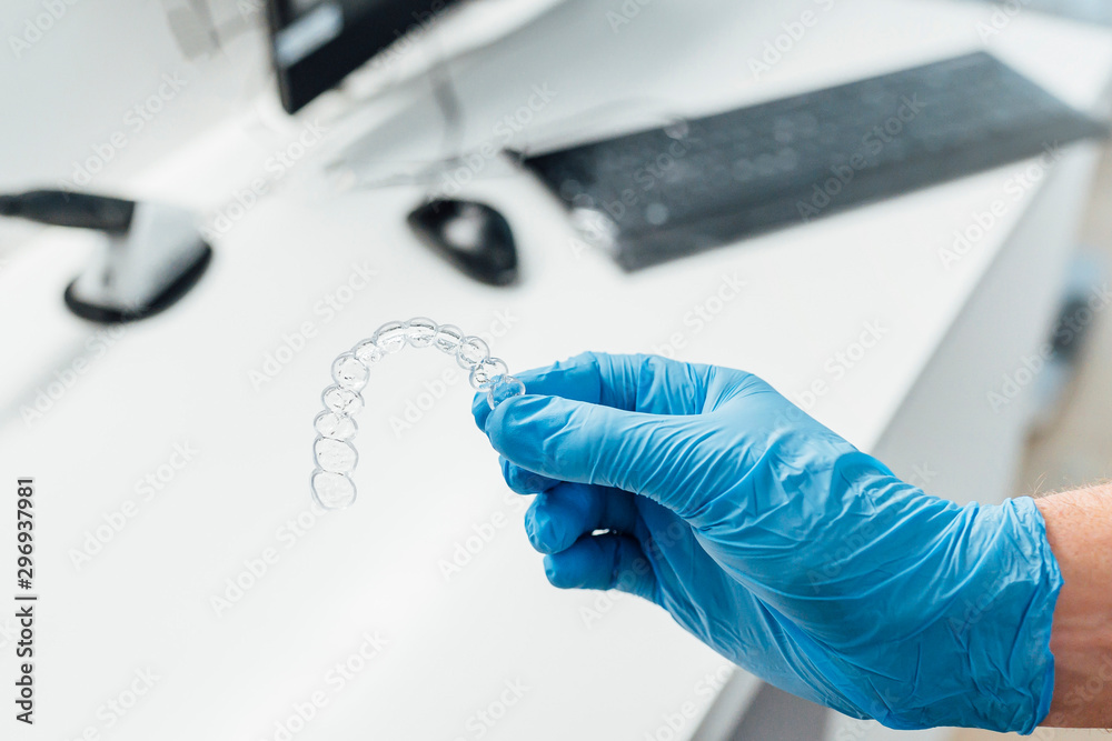 Doctor hand holding a clear dental aligner Doctor hand holding a clear dental aligner