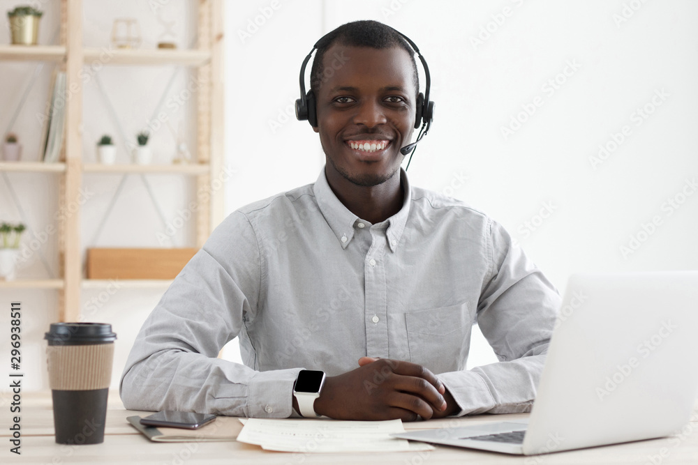 Portrait of smiling african male customer service worker, sitting with ...