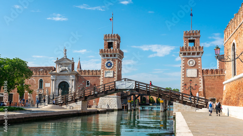 Venice. Panoramic view of Arsenal towers and canals. Girl in red goes on the bridge. Biennale, world modern art exhibition. Famous Venetian landmark. 