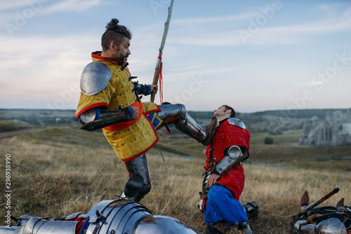 Medieval knight in armor prepares to cut off head