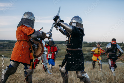 Knights in armour and helmets fight with swords
