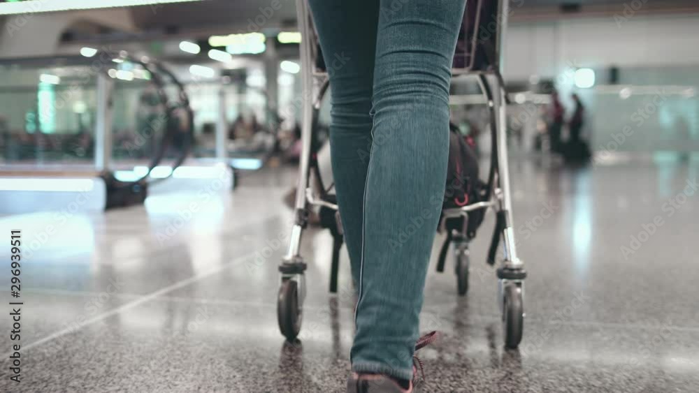 Woman with Luggage Cart Walk at Airport Terminal. Tracking Shot Shows