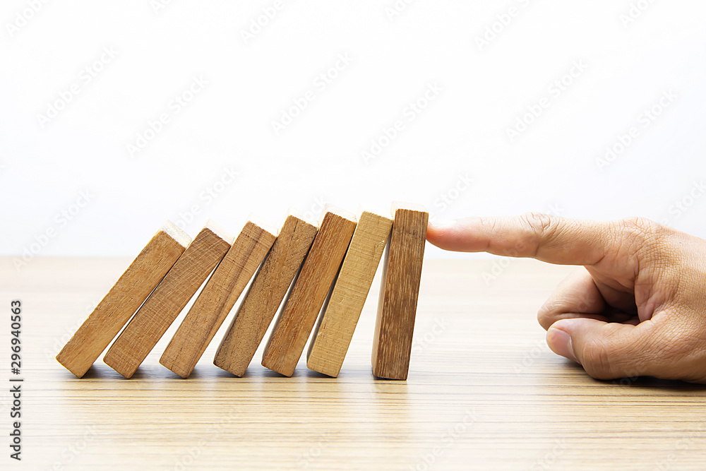 Businessman hand stoped wooden domino effect for risk management and insurance concept.