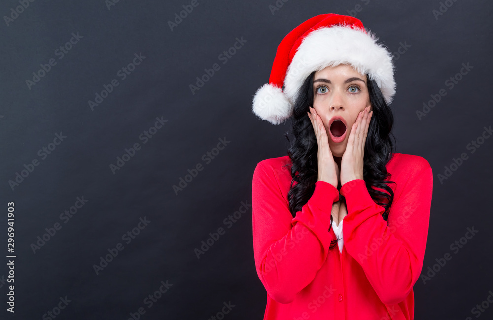 Young woman with a Santa hat on a black background Young woman with a Santa hat on a black background