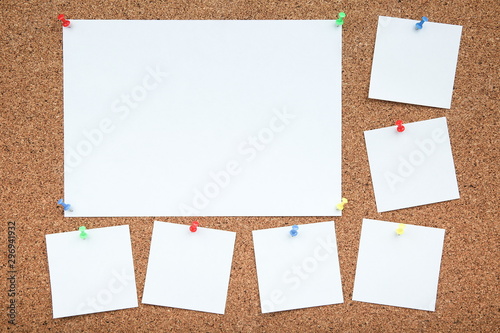 a sheets of paper are attached to the cork Board with a push-buttons. empty note papers pinned on corkboard photo