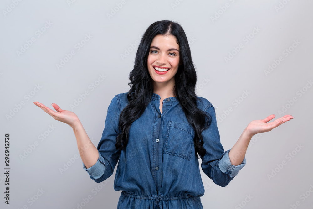 Young woman with a displaying hand gesture on a gray background