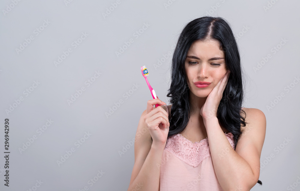Young woman with a toothache on a gray background Young woman with a toothache on a gray background