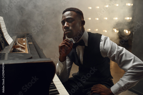 Black grand piano musician poses on the stage